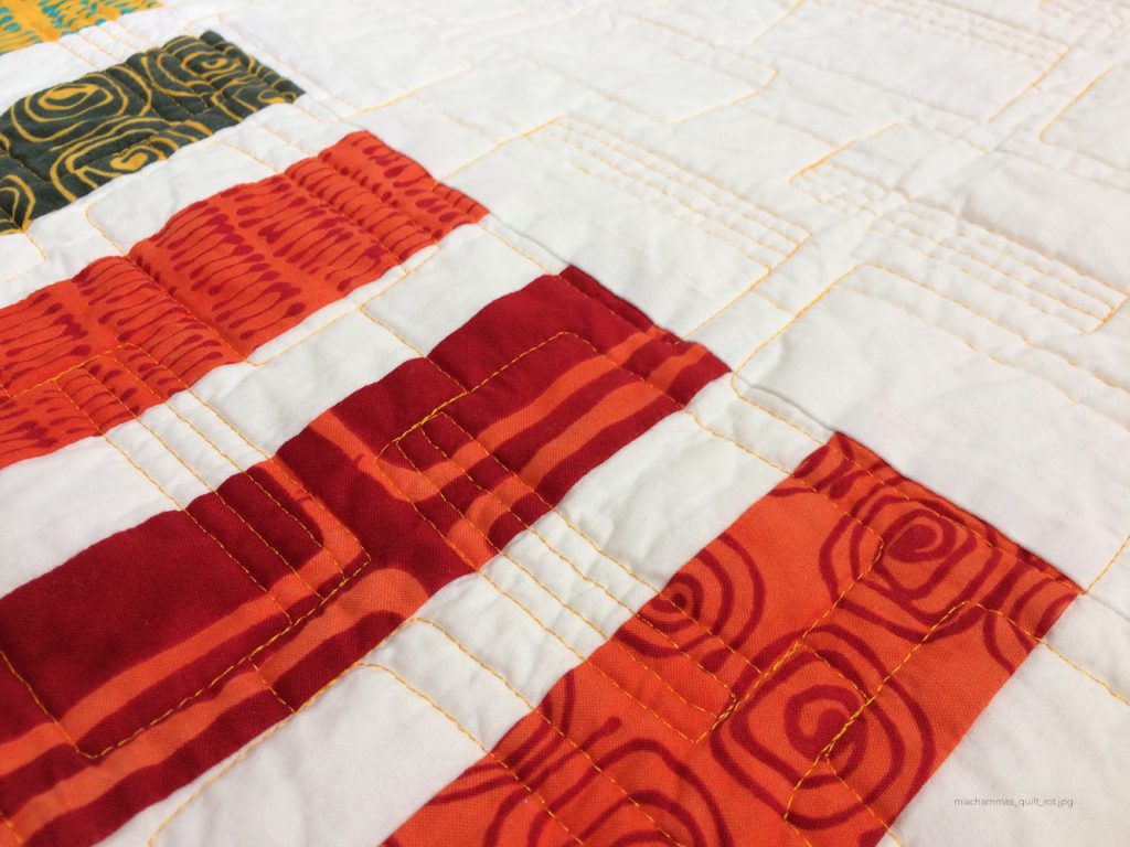 weißer Quilt mit rot-orangen Streifen